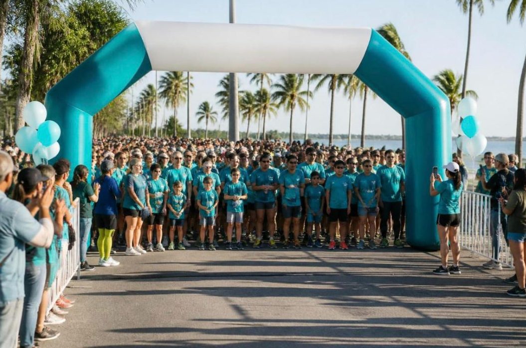Charity 5K start line with runners in teal shirts under an arch